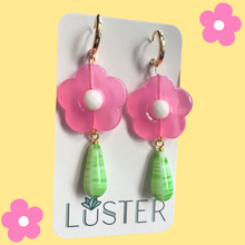 Load image into Gallery viewer, Flower-shaped earrings with pink flowers and green teardrop charms on a Luster branded card against a yellow background.