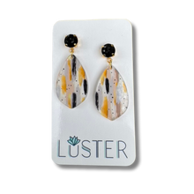 Load image into Gallery viewer, Teardrop-shaped earrings with black and gold accents on a Luster branded card.
