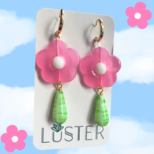 Load image into Gallery viewer, Flower-shaped earrings with pink flowers and green teardrops on a Luster branded card against a blue sky background.
