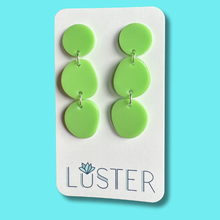 Load image into Gallery viewer, Green circular earrings on a Luster branded card against a blue background
