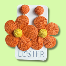 Load image into Gallery viewer, Orange flower-shaped earrings on a Luster branded card against a light green background
