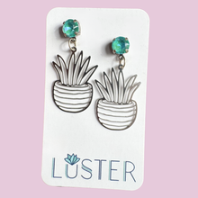 Load image into Gallery viewer, Pendant earrings with plant design on a Luster branded card against a pink background
