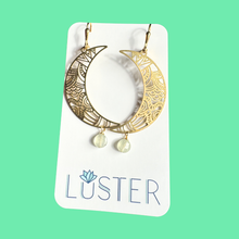 Load image into Gallery viewer, Gold hoop earrings with moon design on a Luster branded card against a green background
