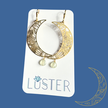 Load image into Gallery viewer, Gold crescent moon earrings with dangling beads on a Luster branded card against a blue background.
