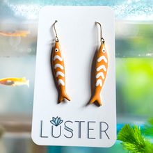 Load image into Gallery viewer, Fish-shaped earrings on a Luster branded card with an aquarium background
