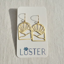 Load image into Gallery viewer, A pair of gold-tone geometric dangle earrings displayed on a white Luster brand card against a light textured fabric background.
