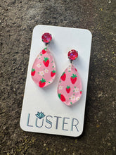 Load image into Gallery viewer, Pair of pink strawberry patterned earrings on a Luster branded card against a textured surface.
